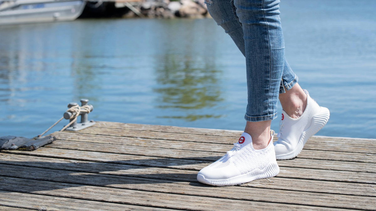 Kuvassa naisen jalat laiturilla, joissa valkoiset Hai sneakerit 